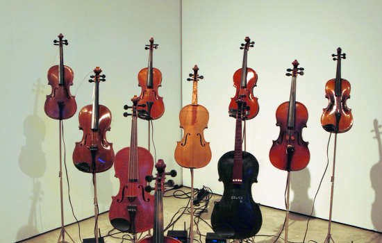 An art piece featuring 10 violins on stands in a triangle formation at Art Windsor-Essex