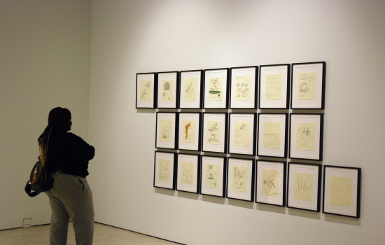 a student stands in front of a wall of framed sketches