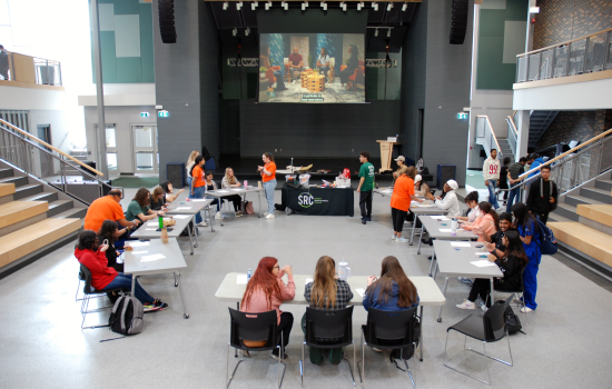 A view of the event, a circle of tables and chairs with students seated making dreamcatchers