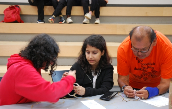 Indigenous elder showing students how to make a dreamcatcher