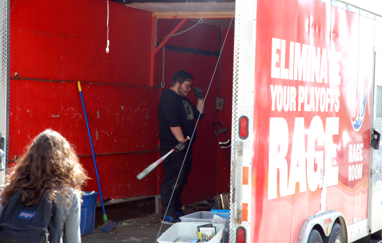 A student holding a baseball bat ready to smash something in the Wreck Room trailer