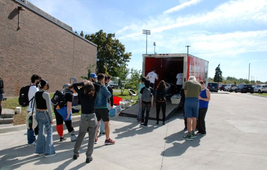 A line up of students waiting for their turn behind the Wreck Room trailer