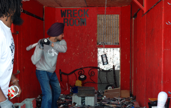 A student holding a baseball bat prepares to hit a vhs tape hanging from a chain