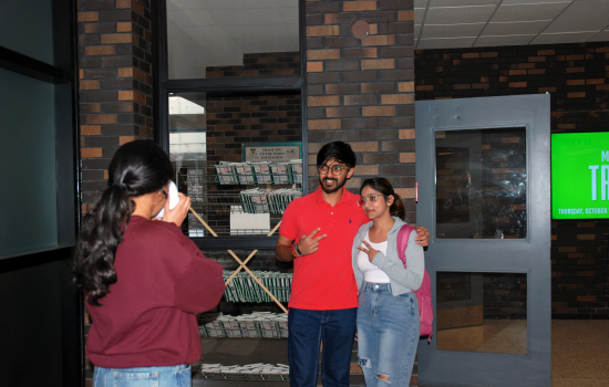 SRC VP South Harnoor taking a polaroid of two students