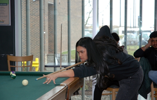 A student lines up their shot on the pool table