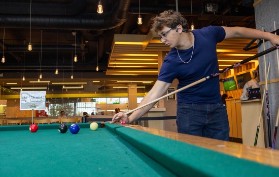 A student lines up his pool shot