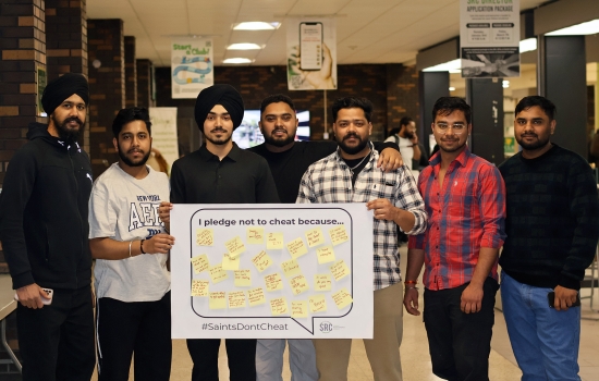 Pratham and a group of students hold up the poster which has been filled with pledges