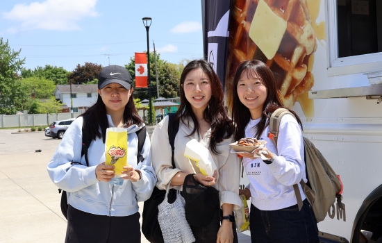 Three students smile with popcorn and waffles